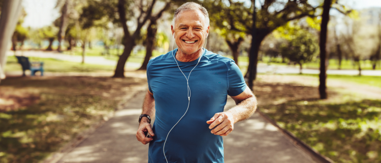 Blog of Zombie Cells: How to Remove Them and Increase Longevity which have image A senior man with a fit physique, wearing a blue athletic shirt and earphones, jogging on a paved path in a green park while smiling. 