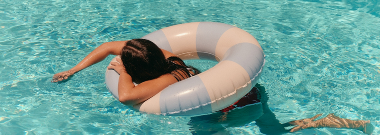 Blog of 7 Sneaky Ways Chlorine Exposure Impacts Your Body (Plus 6 Ways to Protect Yourself) which have image A person floats in a swimming pool on a pastel-striped inflatable ring, resting their head on the side.
