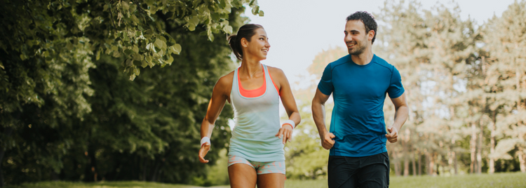 Blog of Magnesium vs. Magnesium Citrate: What’s the Difference? which have image A smiling man and woman jogging together in a lush green park, wearing athletic clothing. 